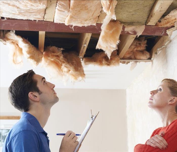 Image of 2 persons staring at a damaged ceiling 