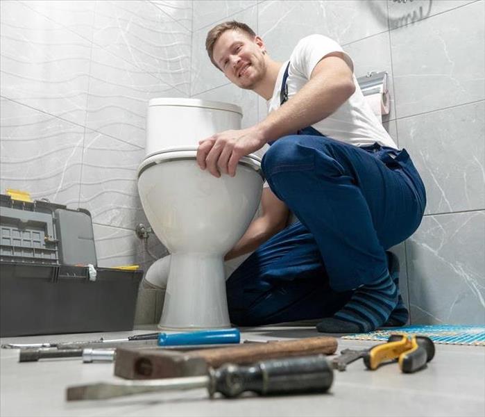 A professional repairing a toilet.