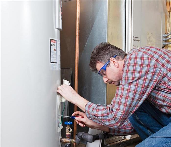 A professional fixing a water heater.