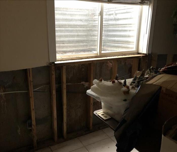 Flood cuts were performed in white wall under window to remove all water damaged material and to begin restoration. 