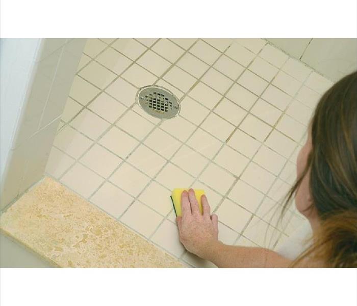 Image of a person cleaning shower floor